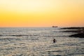 Two girls sit on sup board in the quiet mediterranean sea at sunset in the city of paphos in cyprus. Silhouettes of 2 Royalty Free Stock Photo