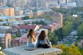 Two girls sit to chat and enjoy the view of Yerevan city in Armenia.