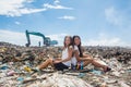 Two girls sitting back to back at garbage dump