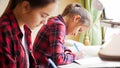 Portrait of two girls sitting behind desk in bedroom and writing homework Royalty Free Stock Photo