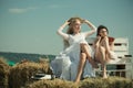 Two girls sitting on bench on hay. Royalty Free Stock Photo