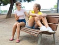 Two girls sitting on bench in park and laughing Royalty Free Stock Photo