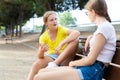 Two girls sitting on bench in park and laughing Royalty Free Stock Photo