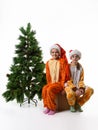 Two girls sitting on a box with toys near an artificial Christmas tree Royalty Free Stock Photo