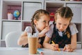 Two girls are sitting at  desk in the classroom at the lesson. One girl whispers gossip to another girl. School friendship Royalty Free Stock Photo