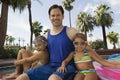 Two girls (7-9) sitting with father by pool portrait. Royalty Free Stock Photo