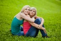 Two girls sitting on the grass, embracing Royalty Free Stock Photo