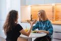 Two girls are sitting at the kitchen table and eating a diet salad. Girlfriends chatting over food Royalty Free Stock Photo