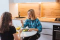 Two girls are sitting at the kitchen table and eating a diet salad. Girlfriends chatting over food Royalty Free Stock Photo