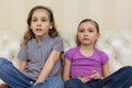 Two girls sitting on a sofa and watching TV intently