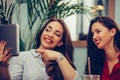 Two girls sitting at a table, using tablet and discuss news Royalty Free Stock Photo