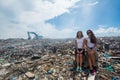 Two girls sitting among trash at garbage dump Royalty Free Stock Photo