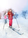 Two girls slide downhill on skies at a winter day