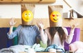 Two girls with smiling paper bags instead of heads sitting in cafe