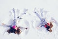 Two Girls on a snow angel shows. Smiling children lying on snow with copy space. Children playing and making a snow Royalty Free Stock Photo