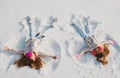 Two Girls on a snow angel shows. Smiling children lying on snow with copy space. Children playing and making a snow Royalty Free Stock Photo