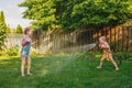 Two girls splashing each other with gardening house on backyard on summer day Royalty Free Stock Photo