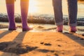 two girls stand on the beach in socks on their bare feet. close-up at sunrise. Royalty Free Stock Photo