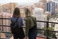 Two girls stand on a hill and look at the beautiful panorama of the Spanish city of Malaga on a warm sunny day.