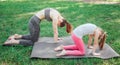 Two girls are standing on carimate and holding their back curved. They are balancing in that pose. Girl are concentrated