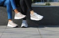 Two girls with a street style showing off their sports shoes.