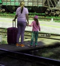 Two girls with a suitcase cross the railway tracks on a wooden deck
