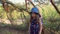 Two girls in summer dresses are climbing a tree in the forest