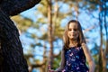 Two girls in summer dresses are climbing a tree in the forest