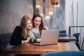 Two girls surfing the net, posting on social networks on a laptop computer and having fun