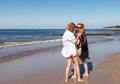 Two girls in swimsuits take pictures of each other with smartphone on the seashore