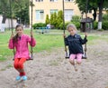 Two girls swing on a swing. Playground