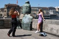 Two girls at the sitting Helvetia bronze statue in Basel, Switzerland