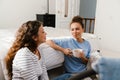 Two girls talking and drinking coffee while sitting over bed at home Royalty Free Stock Photo