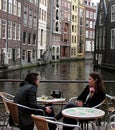Two girls talking at a pavement cafe near the canal in Amsterdam Royalty Free Stock Photo