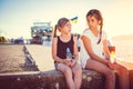 Two girls talking and sitting on a dock Royalty Free Stock Photo