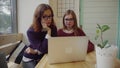 Two girls talking to friends via webchat or having a video chat in cafe