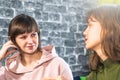 Two girls talks, gossiping or chatting. One of young woman looks at her friend with smile and distrust Royalty Free Stock Photo