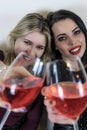 Two girls toast to celebrate an event, and advance their glasses towards the camera Royalty Free Stock Photo