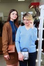 Two girls try on glasses in front of a large mirror in the store. Girls with glasses. Season of sales and discounts. Save money