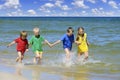 Two girls and two boys in colorful t-shirts running on a sandy beach