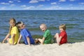 Two girls and two boys in colorful t-shirts sitting on a sandy beach