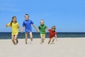 Two girls and two boys in colorful t-shirts walking on a sandy beach