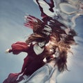 Two girls underwater in a blue and red dress