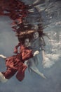 Two girls underwater in a blue and red dress