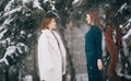 Two girls walk in winter snowy forest during snowfall