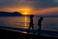 Two girls walking along the beach during sunset Royalty Free Stock Photo