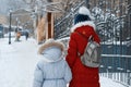 Two girls walking along the winter snowy street of the city, children are holding hands, back view Royalty Free Stock Photo