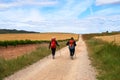 Two girls walking the Camino de Stiago in Spain, immersed in a peaceful countryside, surrounded by meadow fields