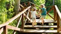 Two girls are walking on a hiking trail with a backpack to a family camp on sunny day. Beautiful wooden road in the forest for