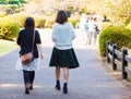 Two girls walking on a road in a city park, Tokyo, Japan. Copy s